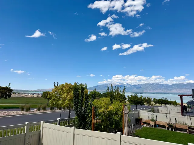 Expansive outdoor space featuring a manicured lawn, a low-maintenance fence, and mature landscaping