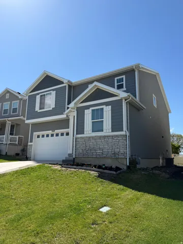 Two-story residence featuring grey siding, white trim, and decorative stone accents
