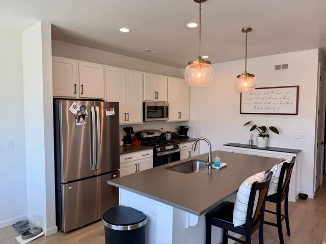 Modern kitchen featuring white cabinetry, stainless steel appliances, and a chevron tile backsplash