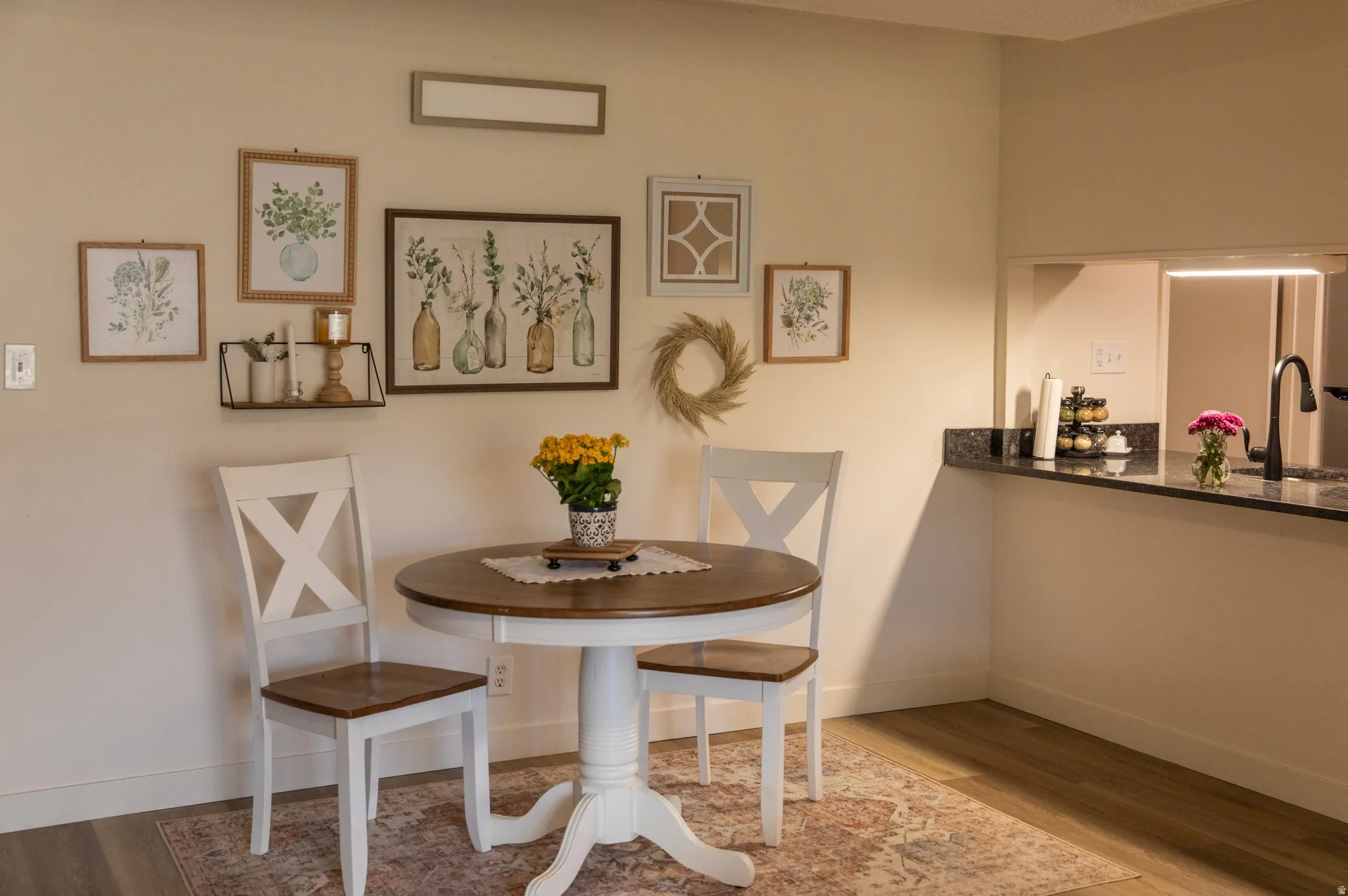 Dining area featuring wood-finish flooring, a pass-through window, and a dark stone countertop with a matte black faucet