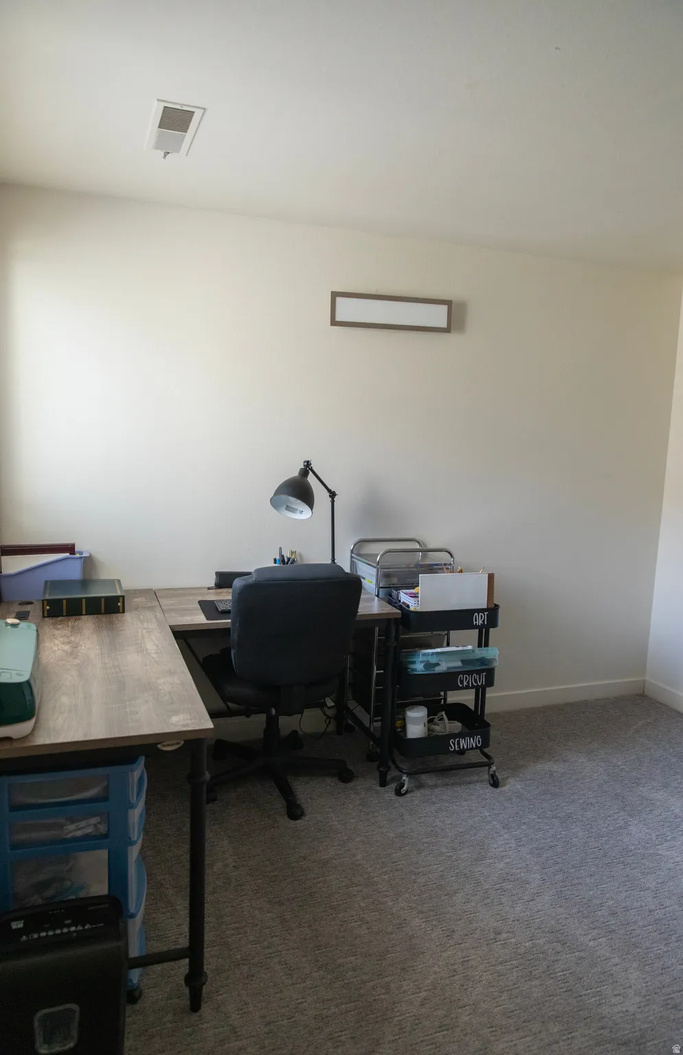 Carpeted room with a wall-mounted rectangular light fixture and ceiling vent