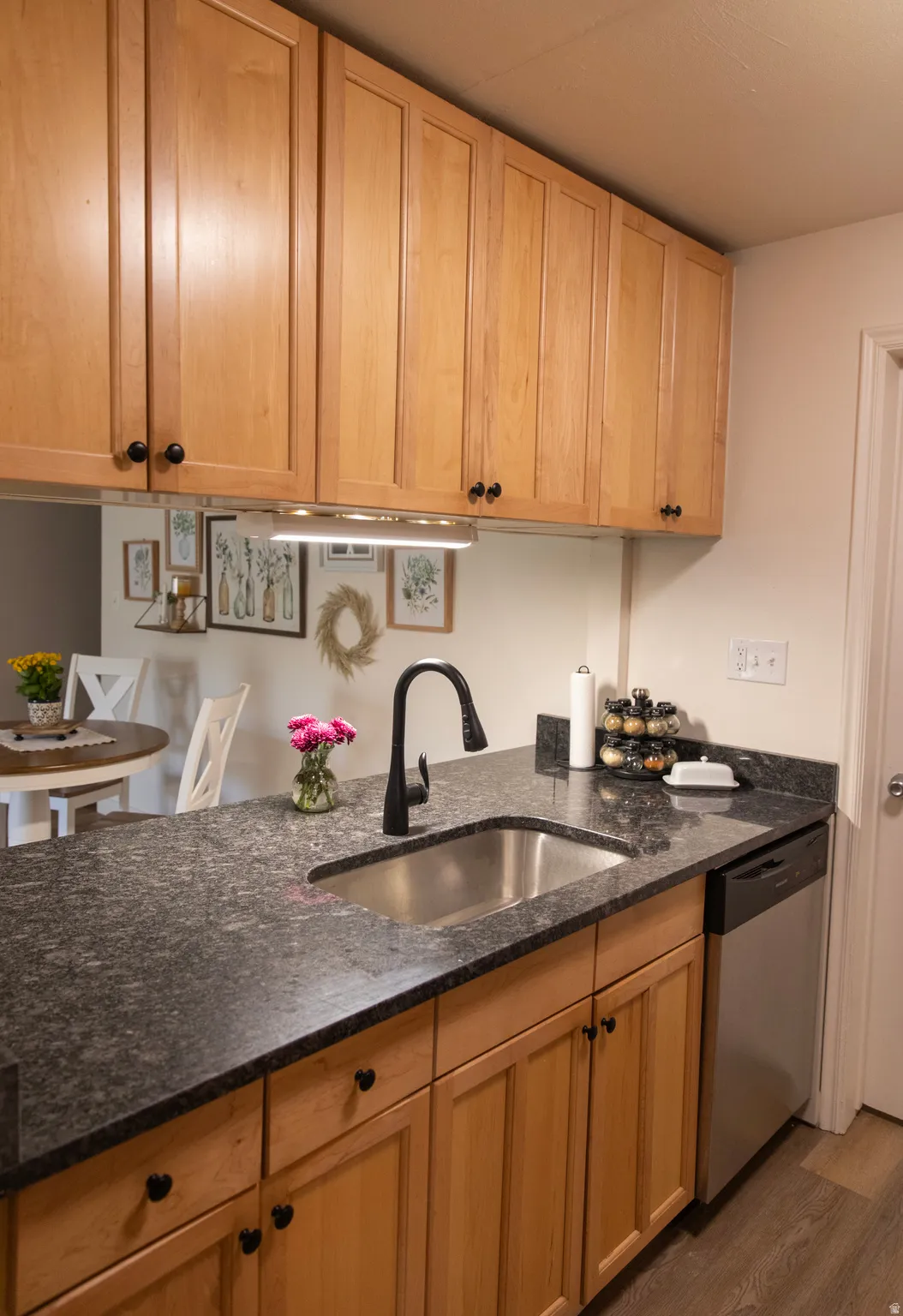 Kitchen workstation featuring a stainless steel sink, black faucet, and dark countertops