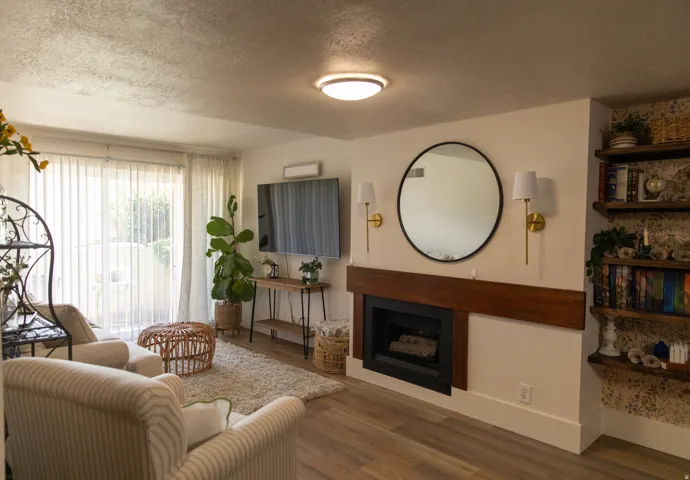 Living area featuring wood-finish flooring, a fireplace with a wood mantle, built-in shelving, and direct access to an outdoor space through sliding glass doors