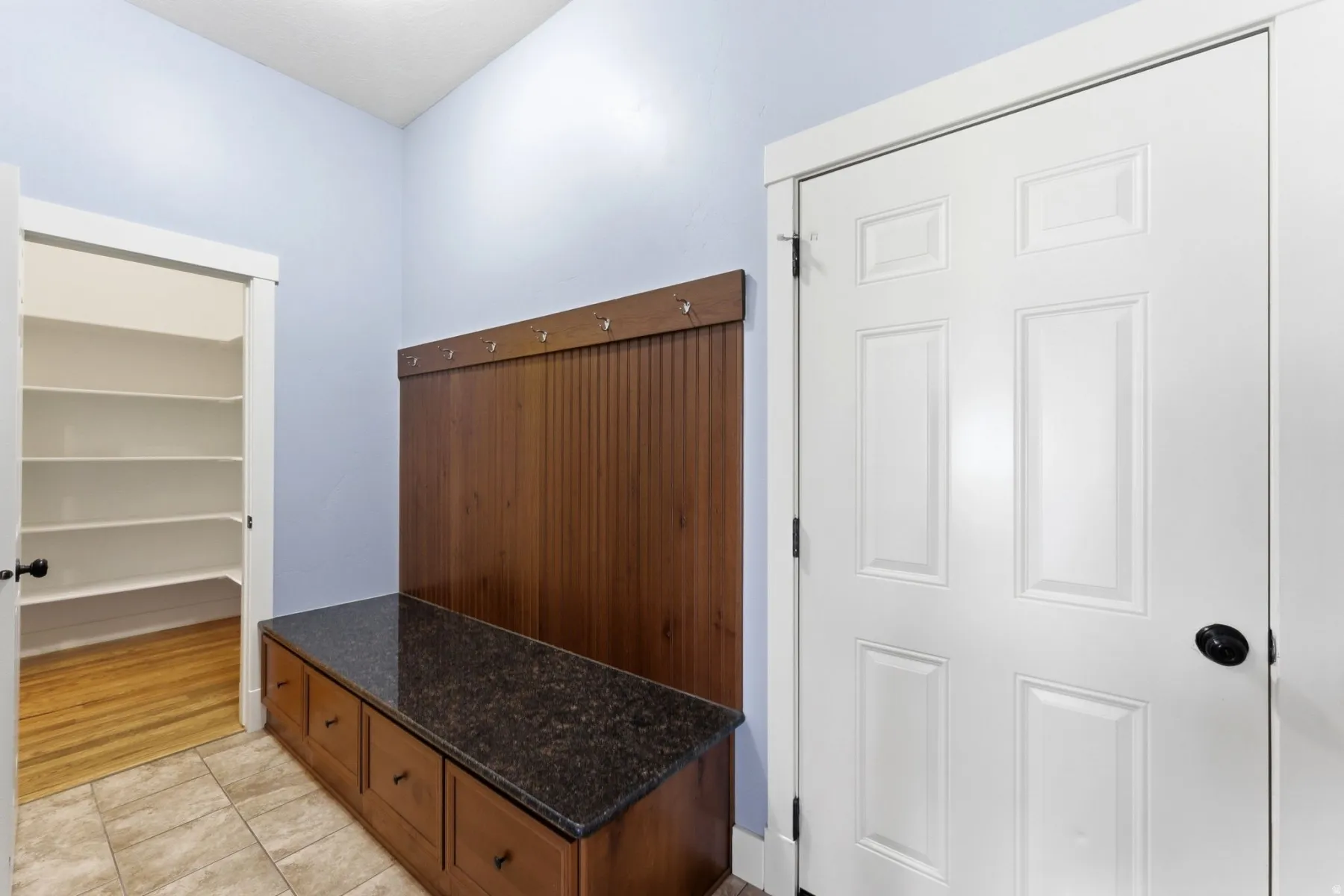 Integrated mudroom bench with built-in storage drawers and a wood-finish beadboard back panel with hooks