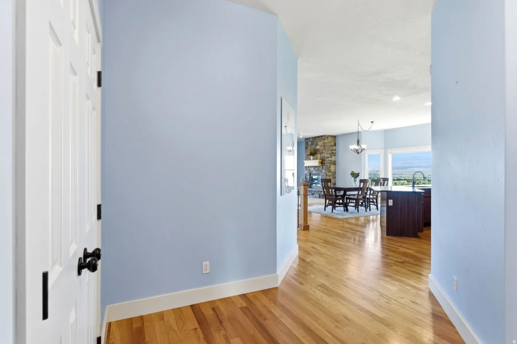 Hardwood flooring in a light wood finish extending from the hallway into an expansive open-concept living area