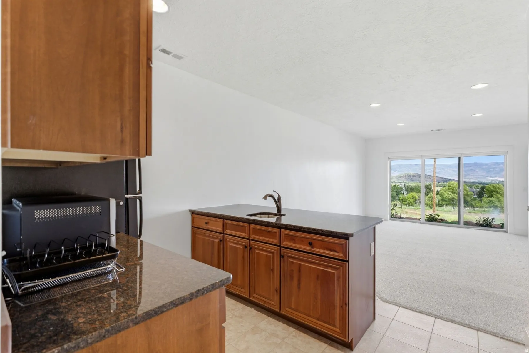Kitchen island with integrated sink and dark countertop, complemented by light wood-finish cabinetry
