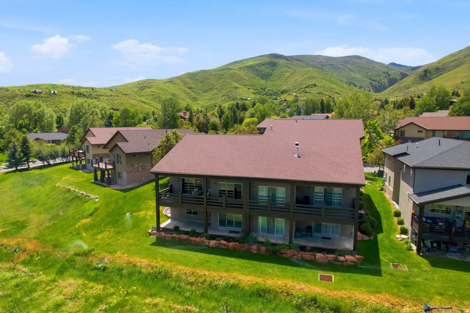 Multi-level residence featuring a brown shingle roof, two-story rear balconies, and lower-level patios