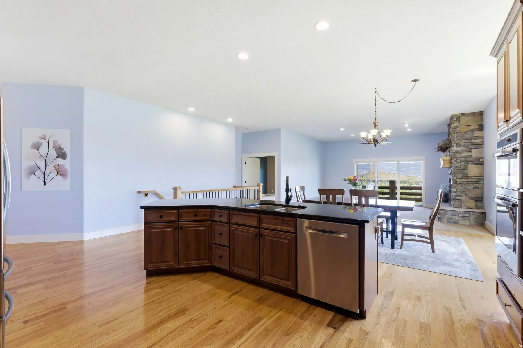 Kitchen island featuring dark wood cabinetry, a black countertop, and a stainless steel dishwasher
