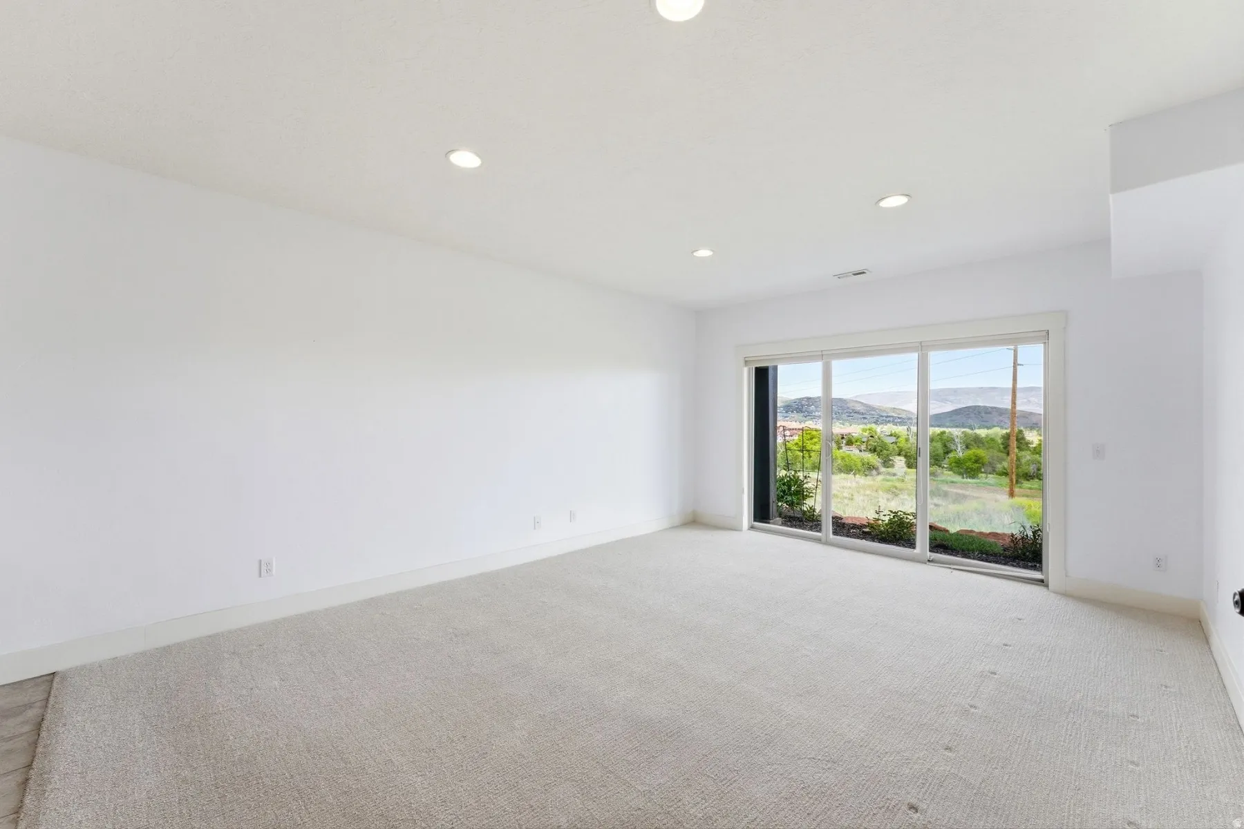 Spacious room featuring light-colored carpeting and white walls