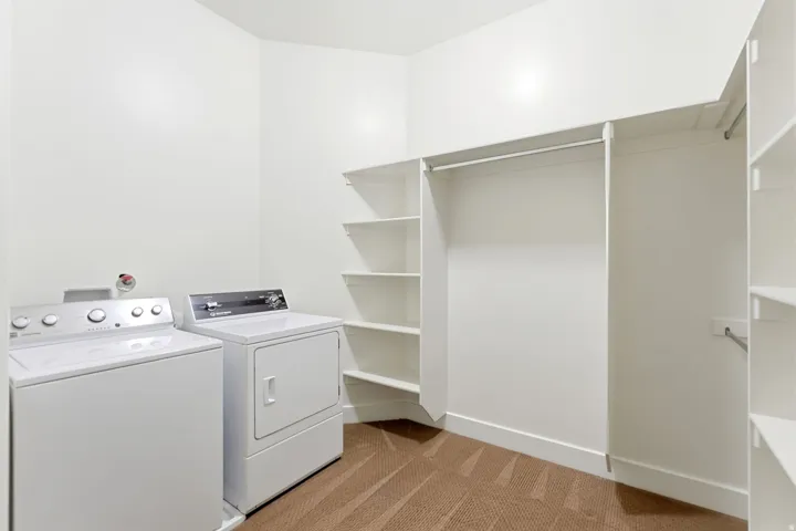 Laundry area with a built-in custom closet system featuring shelving and hanging rods