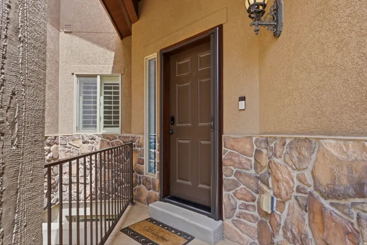 Covered entry featuring a paneled front door, sidelight window, and a stone facade