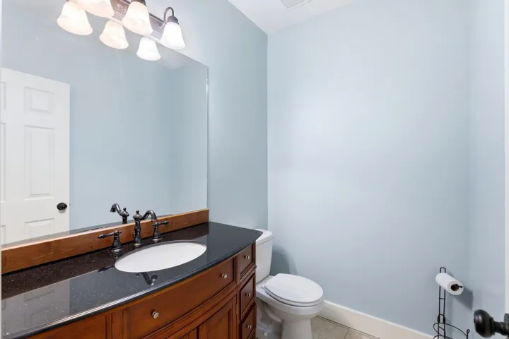 Bathroom featuring a wood vanity with a dark stone countertop and an undermount sink
