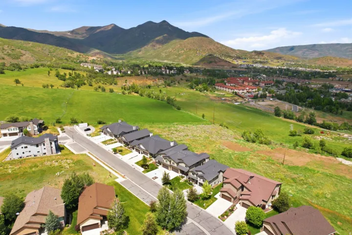 Aerial perspective showcasing a residential development with mountain backdrops and expansive green spaces