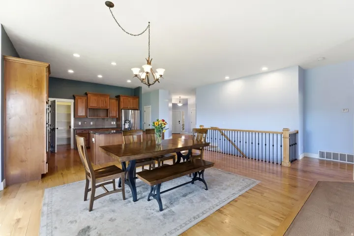 Open-concept dining area featuring wood-finish flooring, recessed lighting, and a chandelier