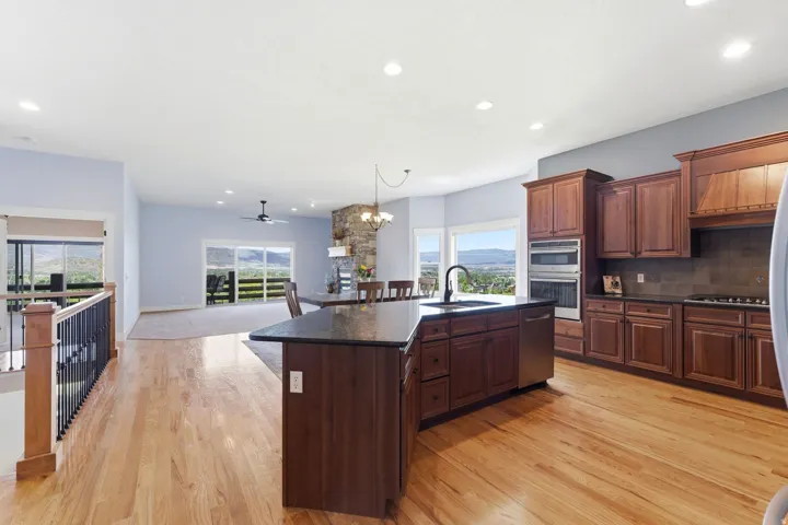 Kitchen featuring hardwood flooring, dark wood cabinetry, and an island with a sink and dark countertop