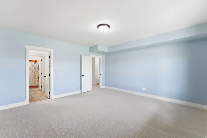 Spacious room featuring light blue painted walls, white trim, light-colored carpeting, and a flush mount ceiling light fixture