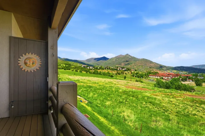 Expansive mountain scenery framing a vibrant green hillside and distant structures with orange tile roofs