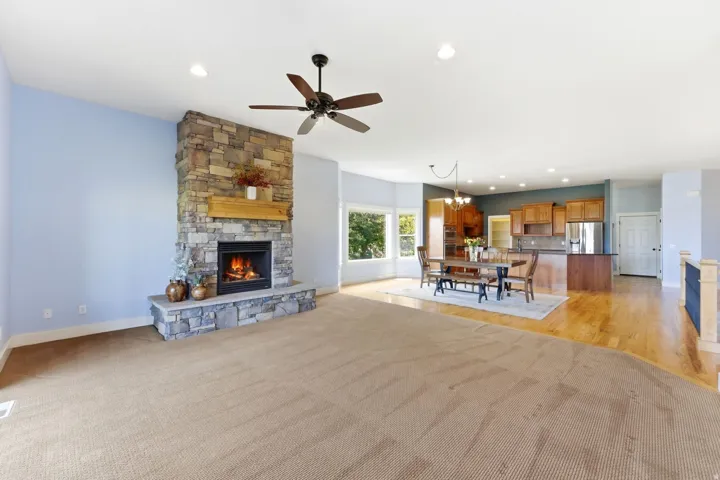 Expansive open-concept living space featuring a stone fireplace with a wood mantel
