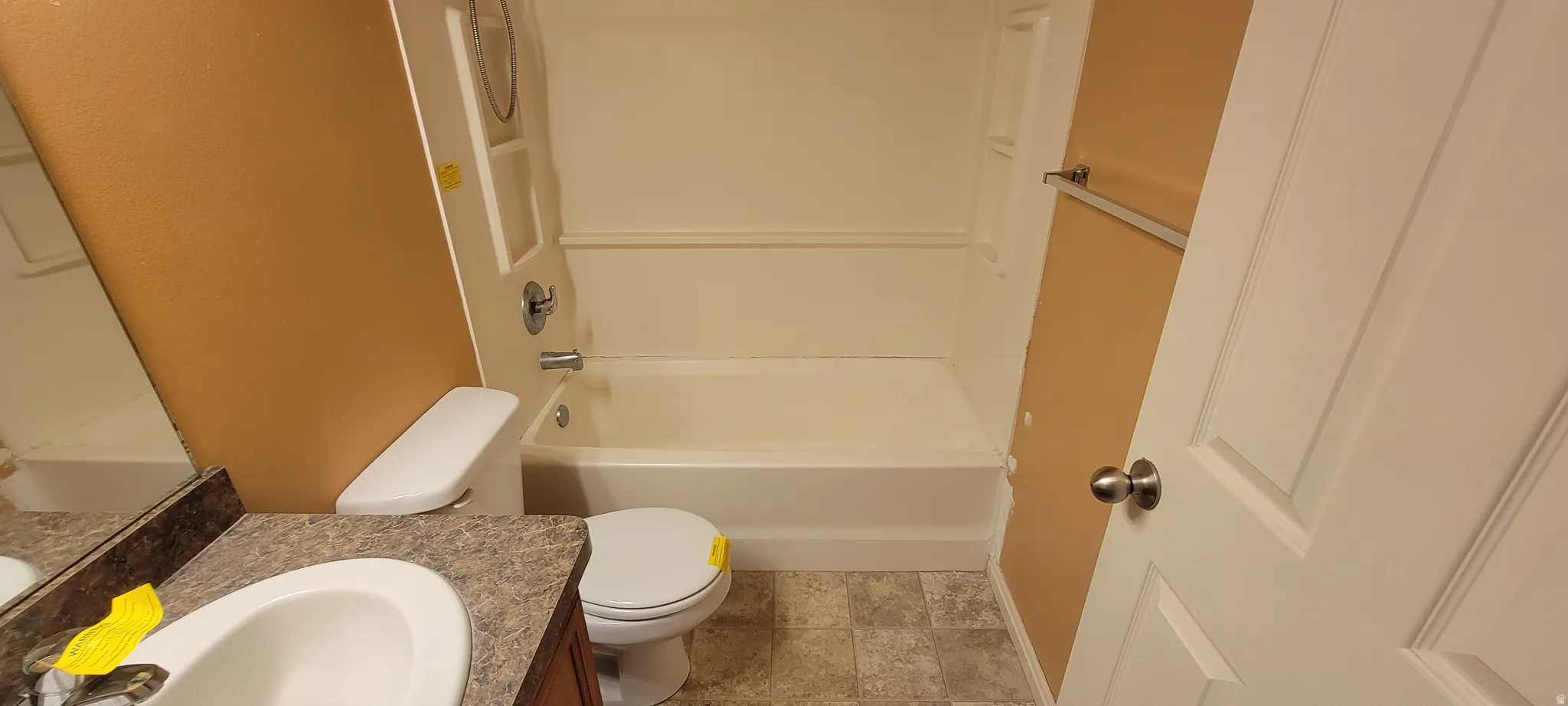 Bathroom featuring a white tub/shower combination, a white toilet, and a vanity with a drop-in sink and a patterned countertop