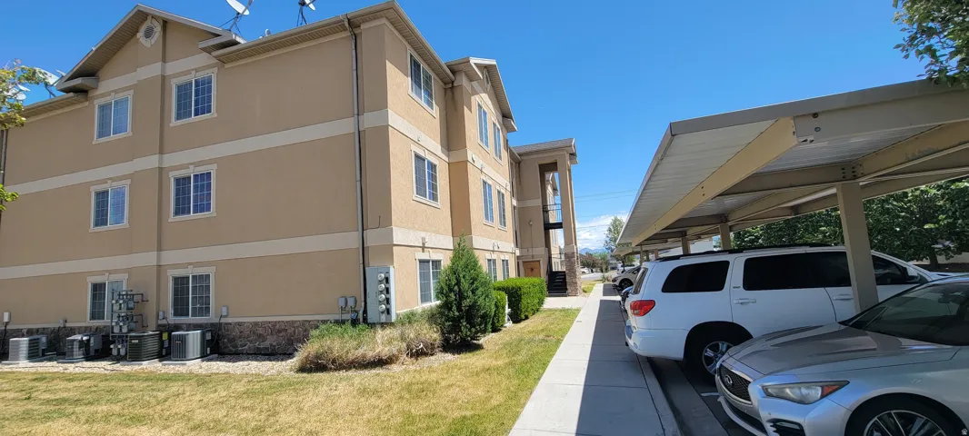 Multi-story building featuring a stucco exterior with decorative banding, multiple windows, and a stone-clad base