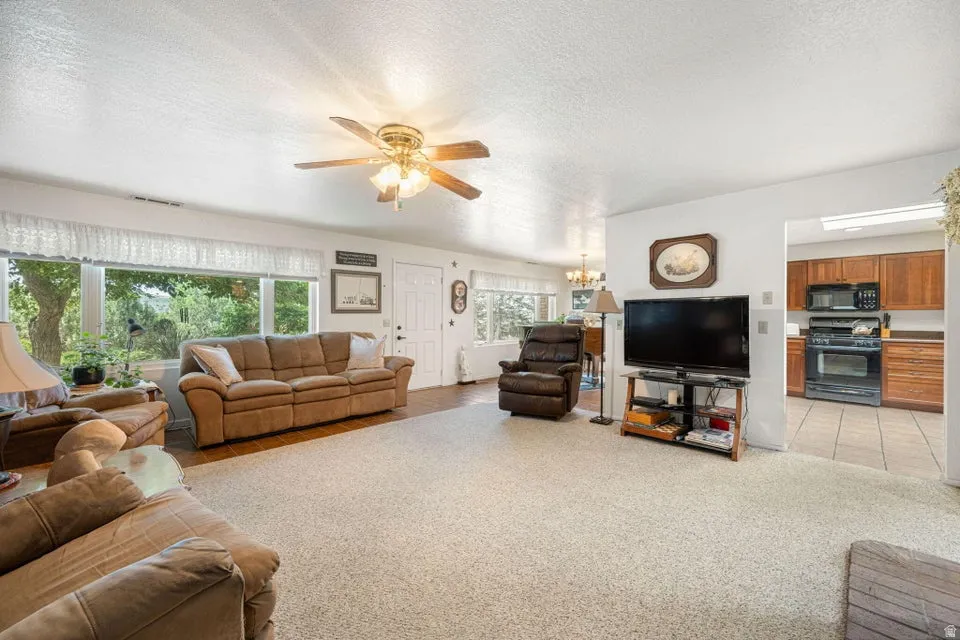 Spacious living area featuring light-toned carpeting and wood-finish flooring