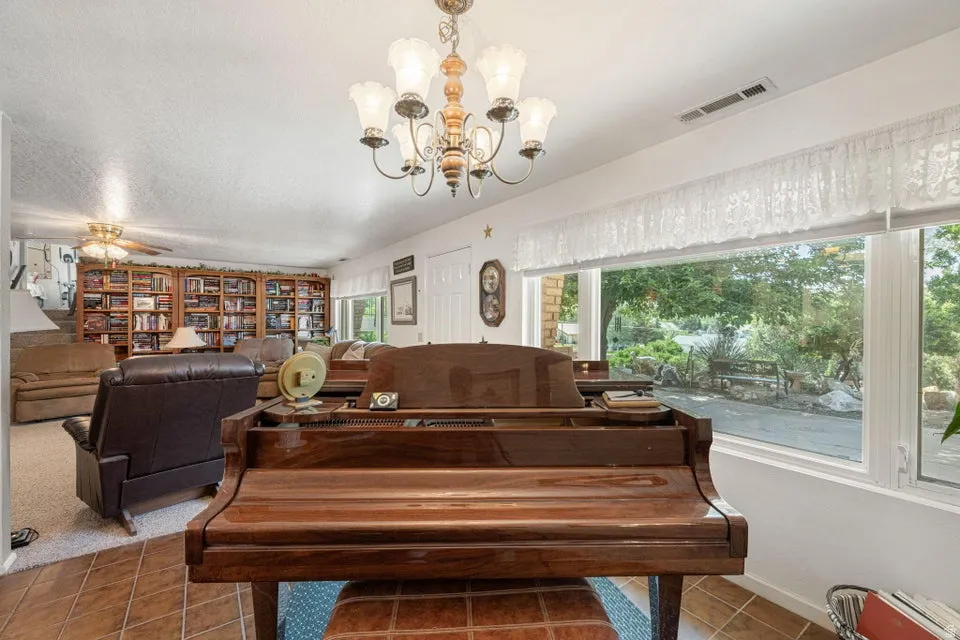Spacious interior featuring a large window, tiled flooring, built-in shelving, and a ceiling fan