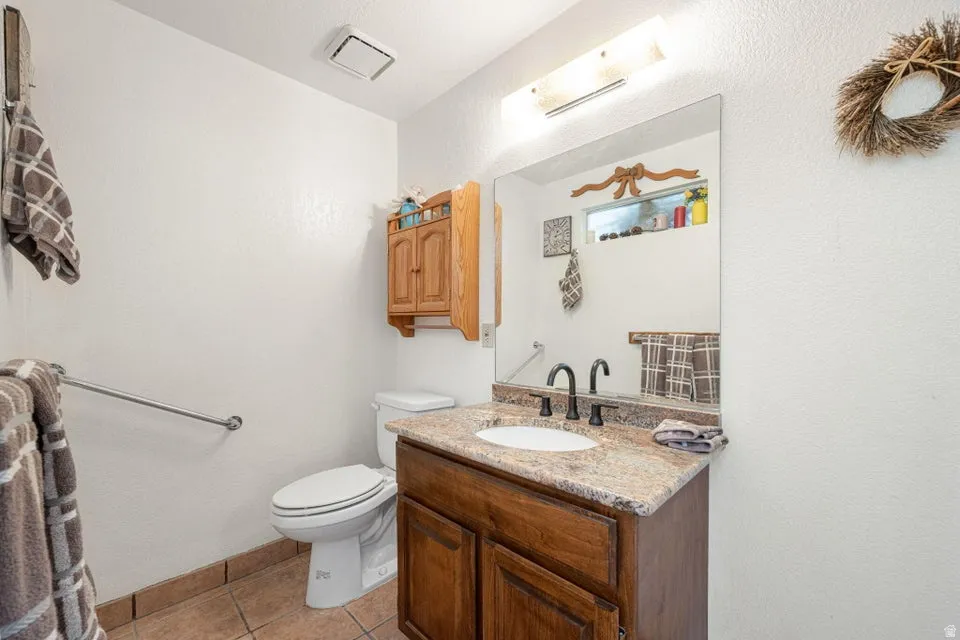 Bathroom featuring a wood-finish vanity with a granite-style countertop and an undermount sink