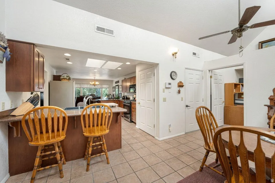 Kitchen and dining area featuring a breakfast bar with seating, recessed lighting, and a ceiling fan