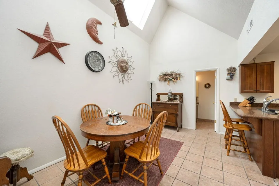 Dining area featuring a vaulted ceiling with skylight, tile flooring, and a breakfast bar with stone-finish countertop