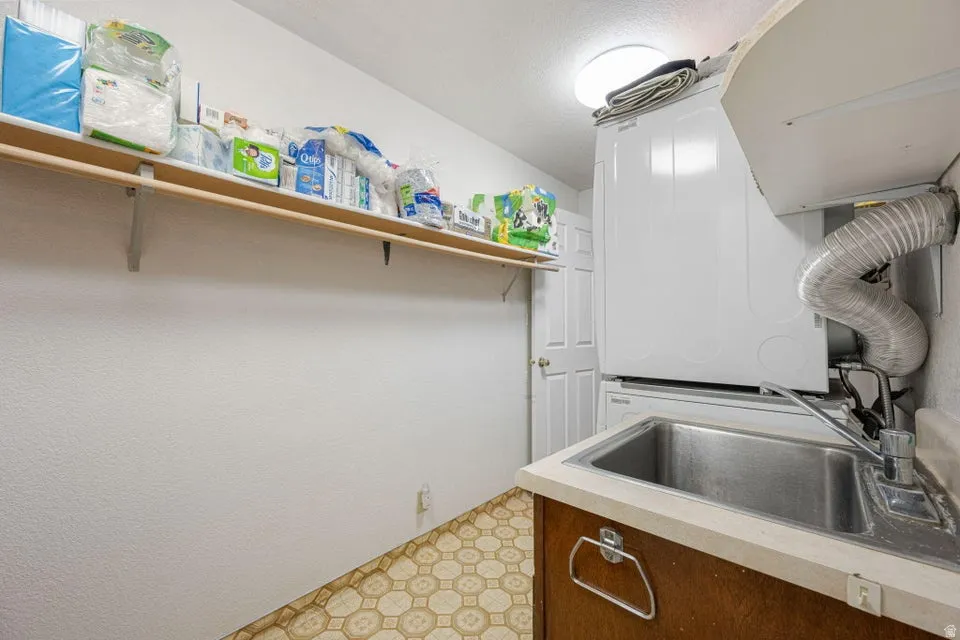Laundry area featuring a utility sink, wood-finish cabinetry, and patterned vinyl flooring