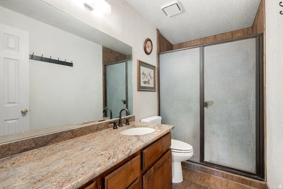 Bathroom featuring a single vanity with a stone-finish countertop, undermount sink, and dark-finish faucet