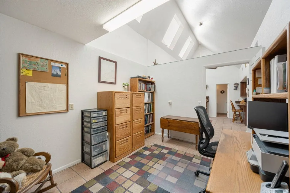 Interior space featuring a vaulted ceiling with skylights, tile flooring, and light-colored walls