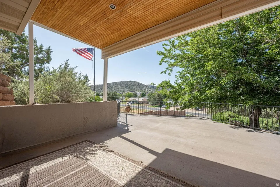 Expansive concrete patio featuring a wood-finish ceiling, metal railings, and a concrete half-wall