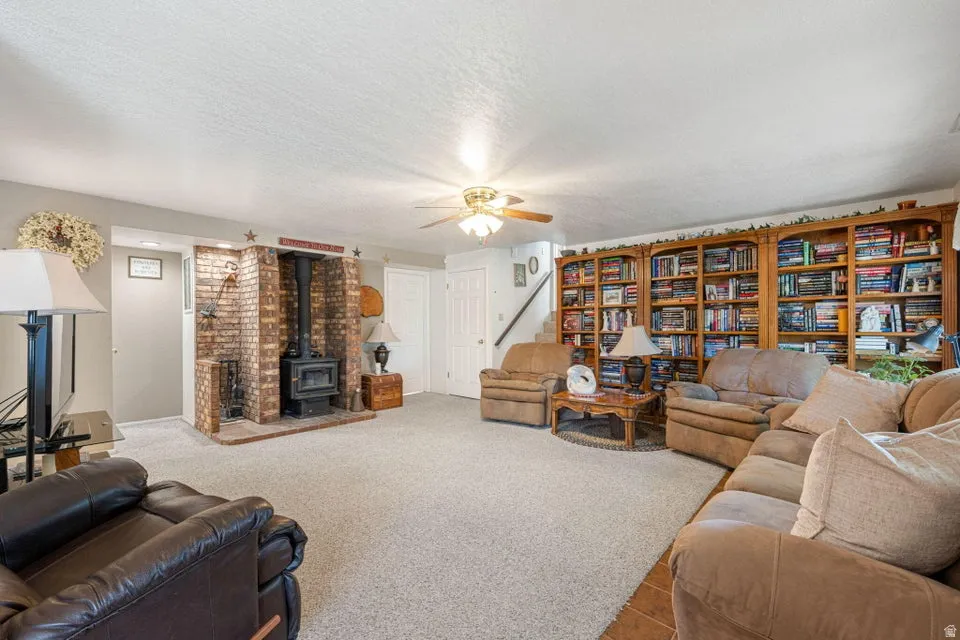 Spacious living area featuring a brick-surround wood-burning stove and a full wall of built-in wood shelving