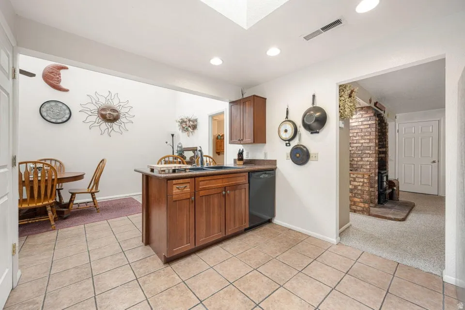 Kitchen featuring a central island with an integrated sink, wood cabinetry, and tile flooring
