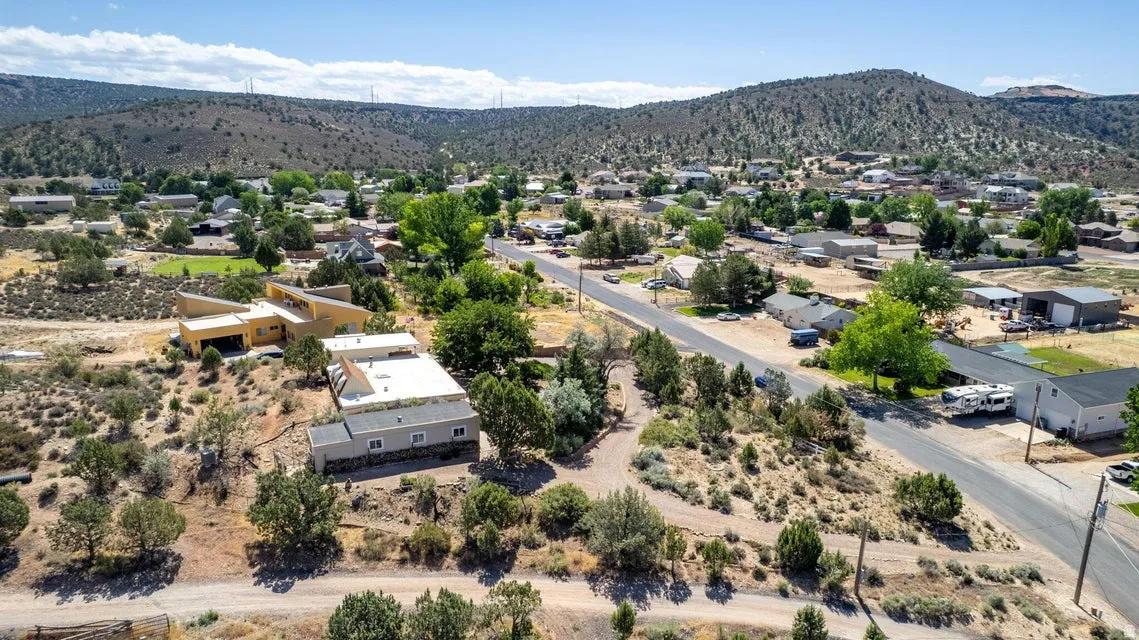 Aerial perspective featuring a residential area with a paved road and surrounding natural landscaping