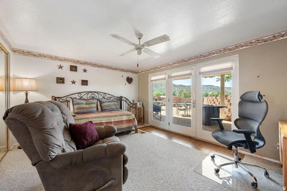 French doors opening to an outdoor patio with mountain scenery, ceiling fan, and carpeted flooring