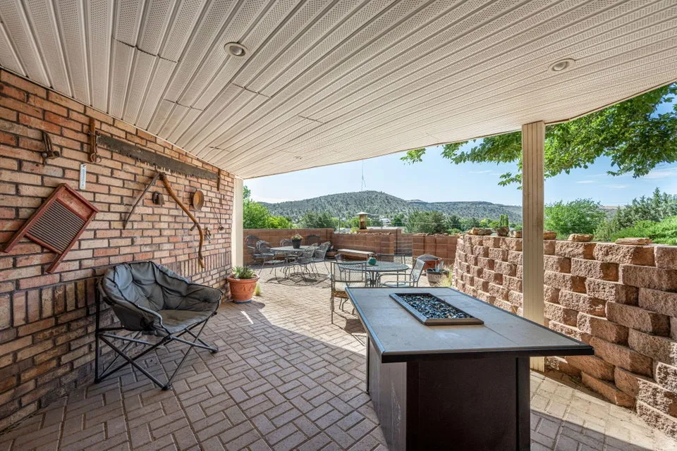 Covered patio featuring brick-laid flooring, recessed lighting, and a stone-clad retaining wall