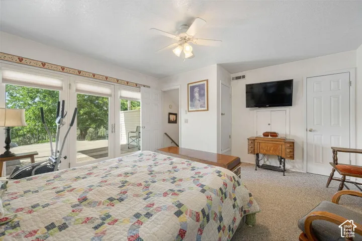 Carpeted room featuring a ceiling fan with integrated lighting, dual French doors opening to an exterior area, and a wall-mounted flat-screen television