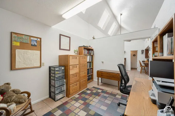 Interior space featuring a vaulted ceiling with skylights, tile flooring, and light-colored walls