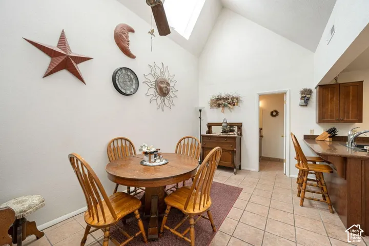 Dining area featuring a vaulted ceiling with skylight, tile flooring, and a breakfast bar with stone-finish countertop