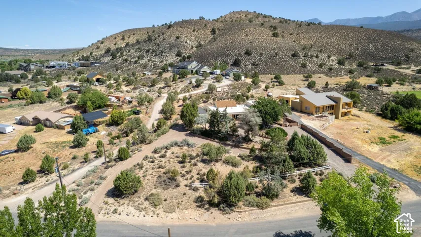 Expansive property featuring a modern architectural residence with a distinctive roofline, a paved driveway, and established natural landscaping