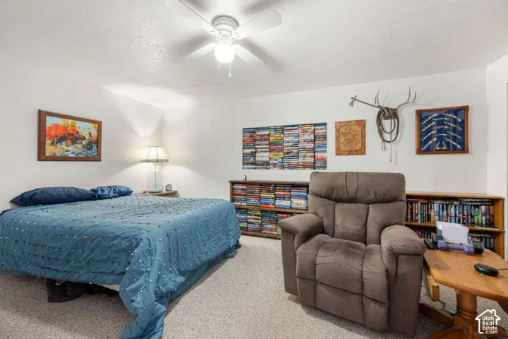 Carpeted room featuring a ceiling fan with integrated lighting, built-in shelving, and white walls