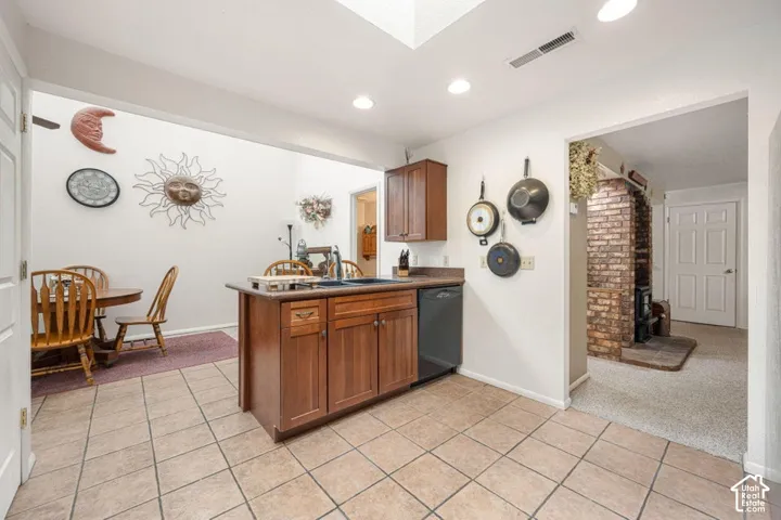 Kitchen featuring a central island with an integrated sink, wood cabinetry, and tile flooring