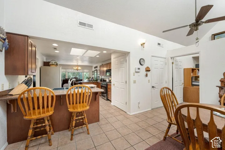 Kitchen and dining area featuring a breakfast bar with seating, recessed lighting, and a ceiling fan