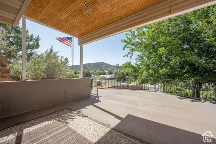 Expansive concrete patio featuring a wood-finish ceiling, metal railings, and a concrete half-wall