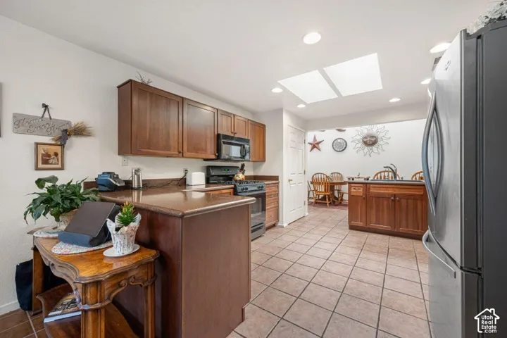 Kitchen featuring warm wood cabinetry, dark countertops, and stainless steel appliances