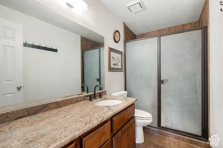 Bathroom featuring a single vanity with a stone-finish countertop, undermount sink, and dark-finish faucet