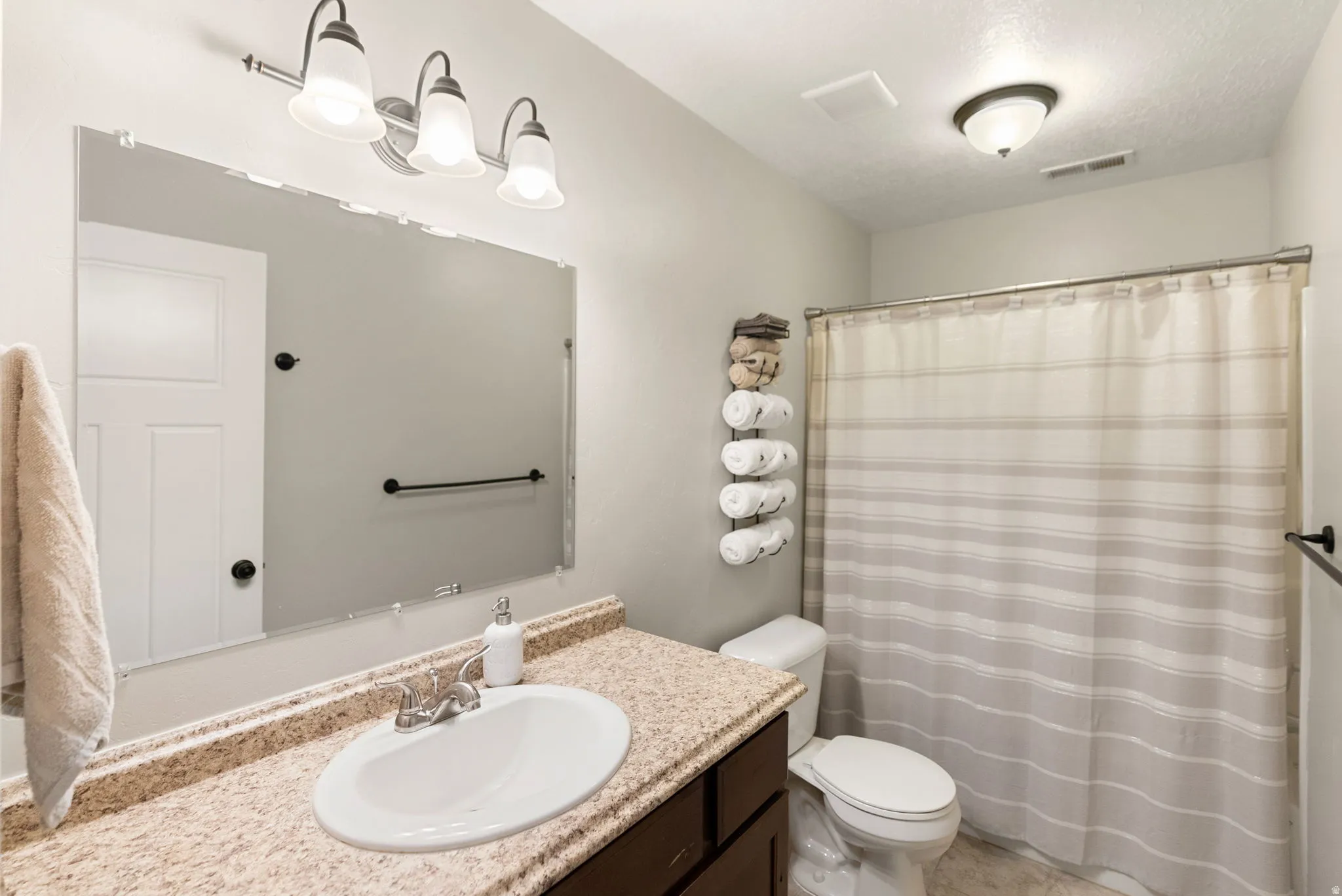 Bathroom featuring a vanity with a light-colored countertop, an undermount sink, and a chrome faucet