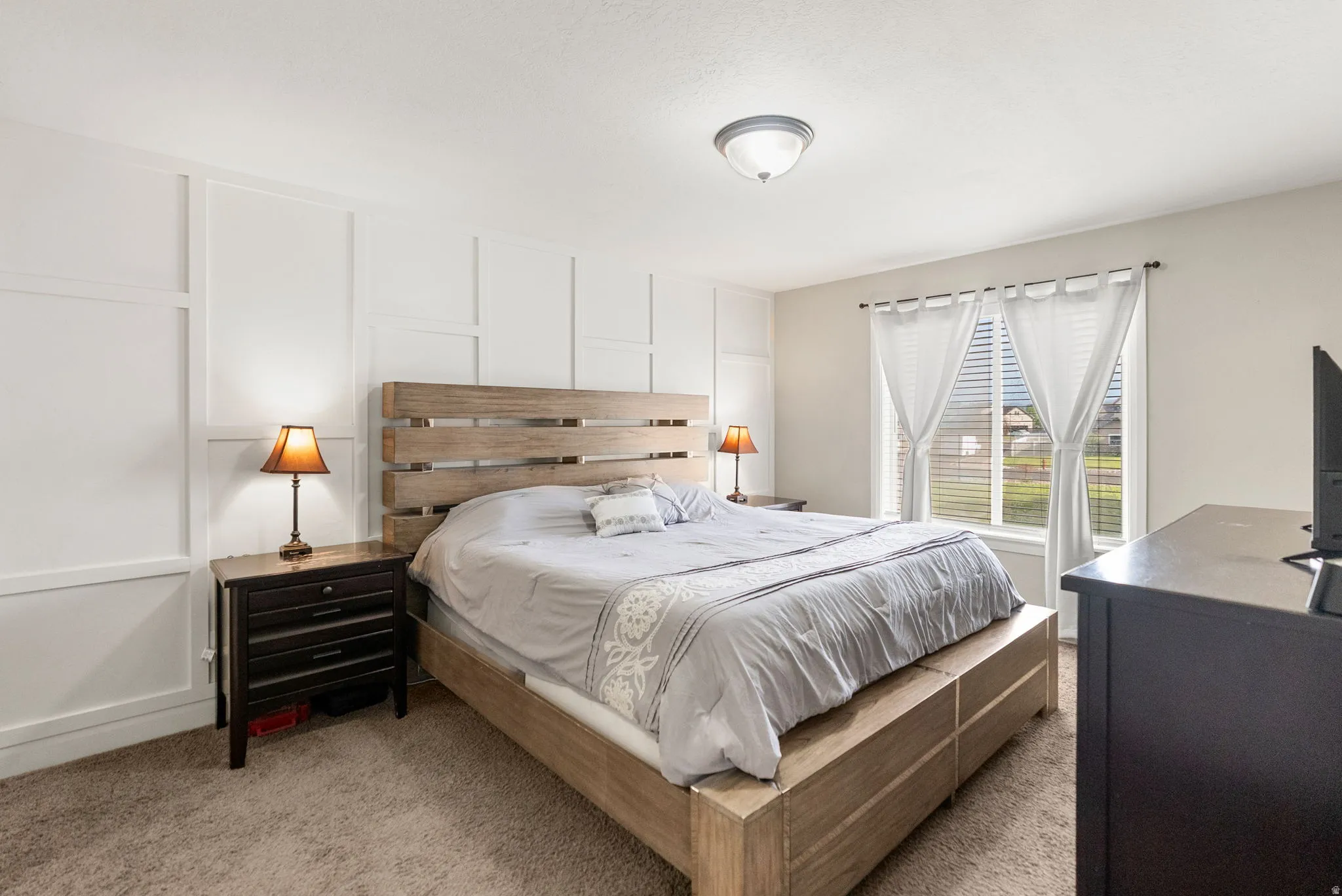 Bedroom featuring board and batten accent wall, neutral carpeting, and a window with blinds